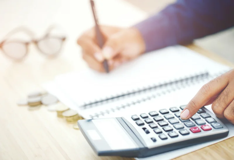 A UK household reviewing their budget using a calculator to save money on everyday expenses.