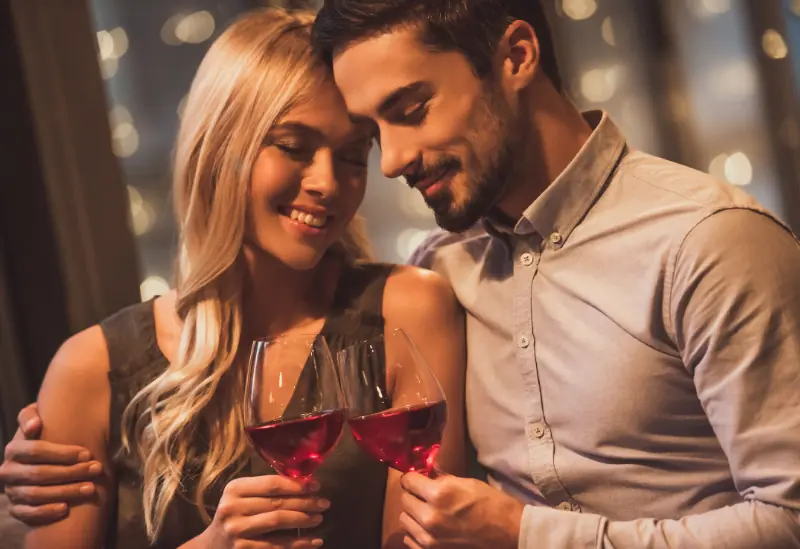 Romantic indoor date night with a couple having a conversation, smiling and sharing wine.